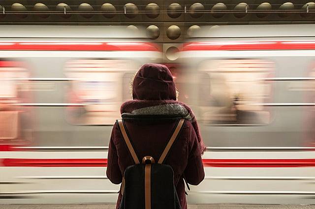 通過電車を見送るバックパッカーの画像