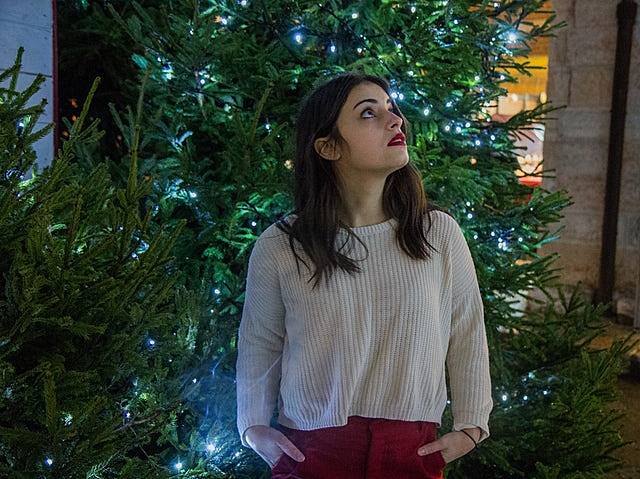 クリスマスツリーのそばで1人たたずむ女性の写真