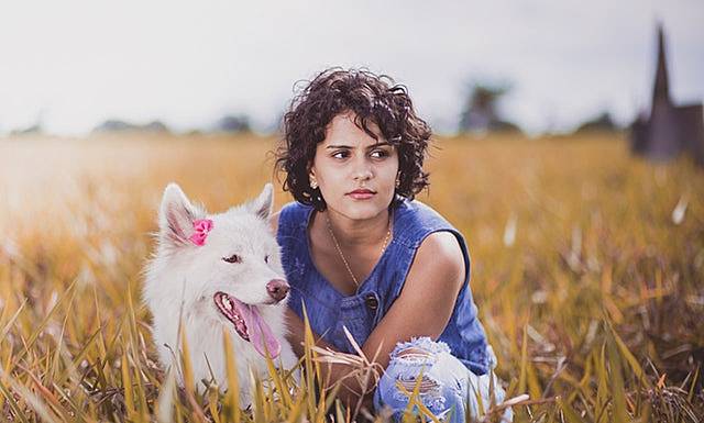女性が犬と一緒にたたずんで座り込む画像