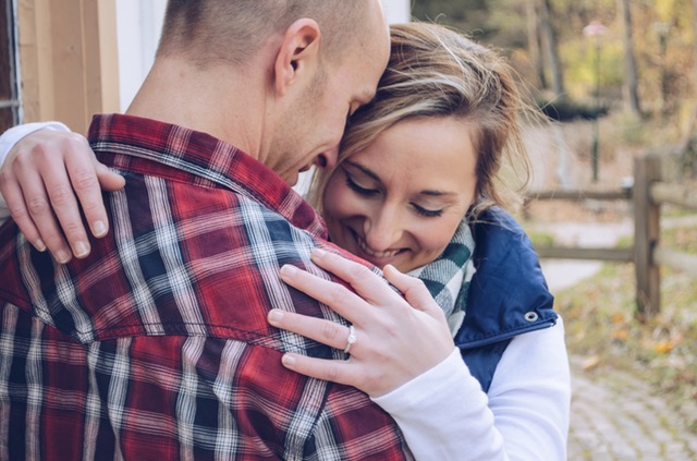 チェック柄のシャツを着ている男性と抱き合う結婚指輪をつけた女性の画像