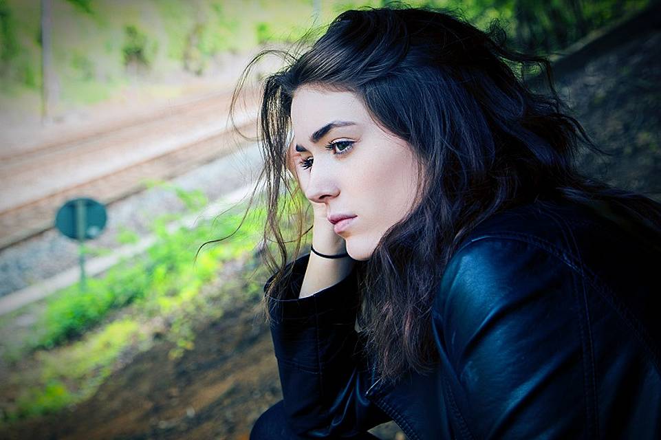 何かを待つようにして頬杖をつきひとり考える女性の写真